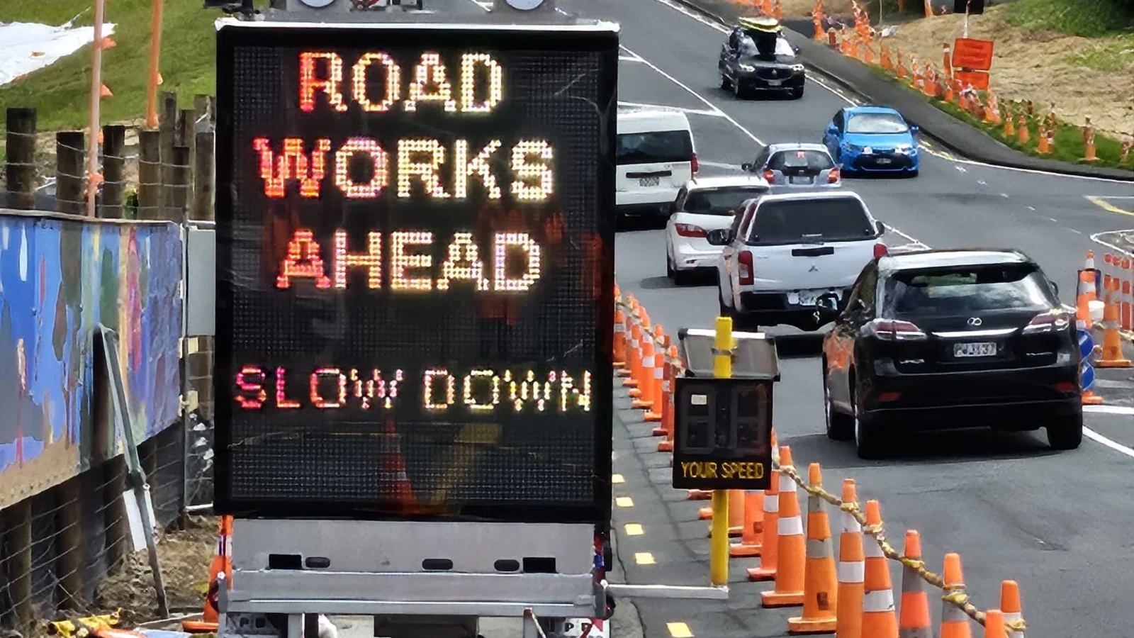 Truck mounted VMS board displaying roadworks ahead and slow down messages
